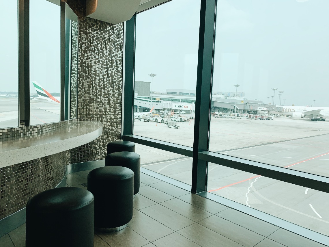 A toilet with chairs, mirrors and a view of planes in Changi Airport